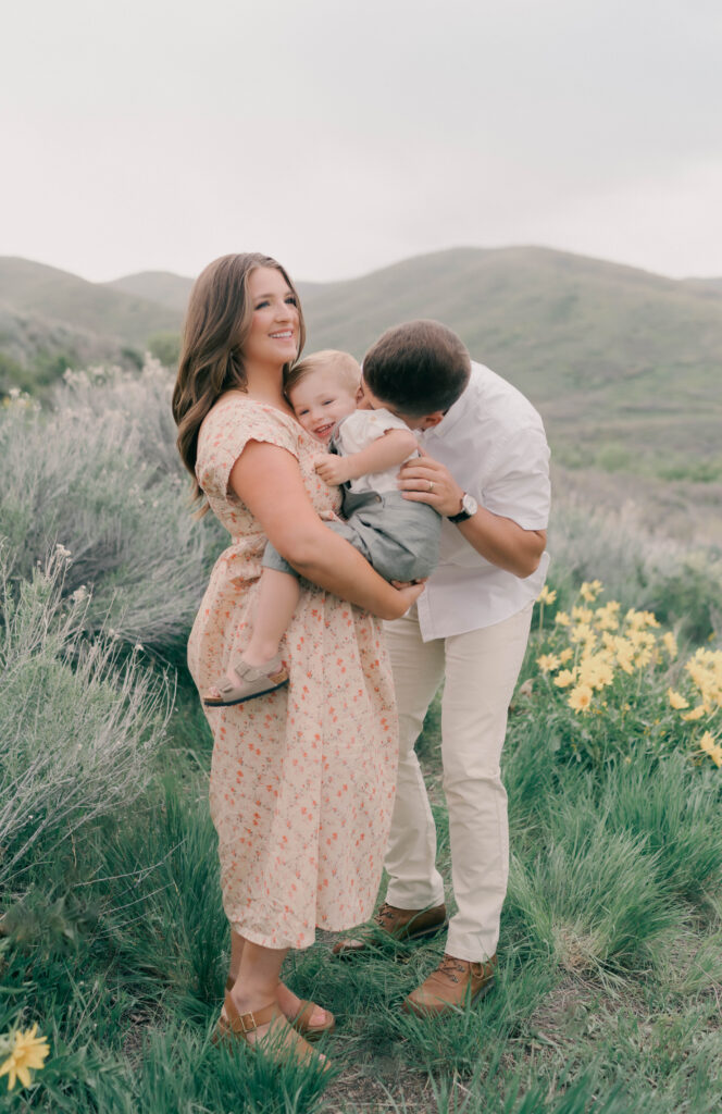 mom holding toddler laughing maternity photos in the mountains