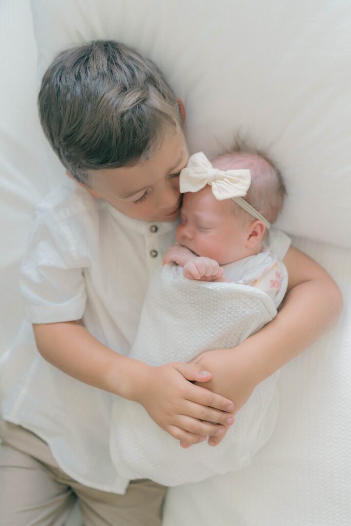 toddler holding newborn for at home newborn session in utah. Captured by talented utah newborn photographer