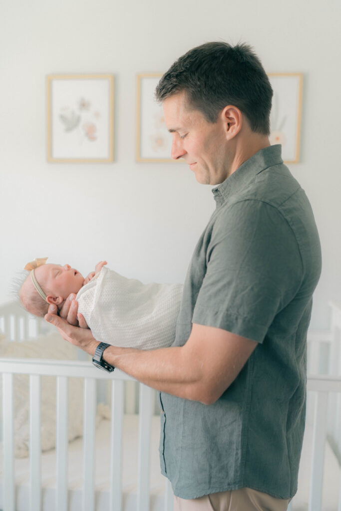 dad in the nursery holding newborn during at newborn photos. Captured by utah newborn photographer